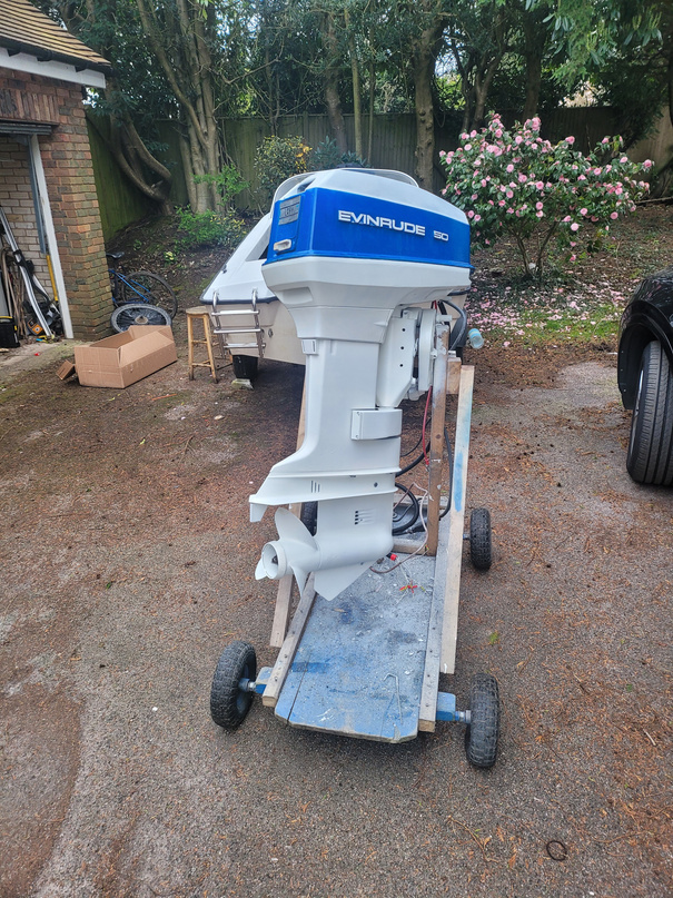 The finished outboard reassembled in Evinrude livery on a roll-out cart