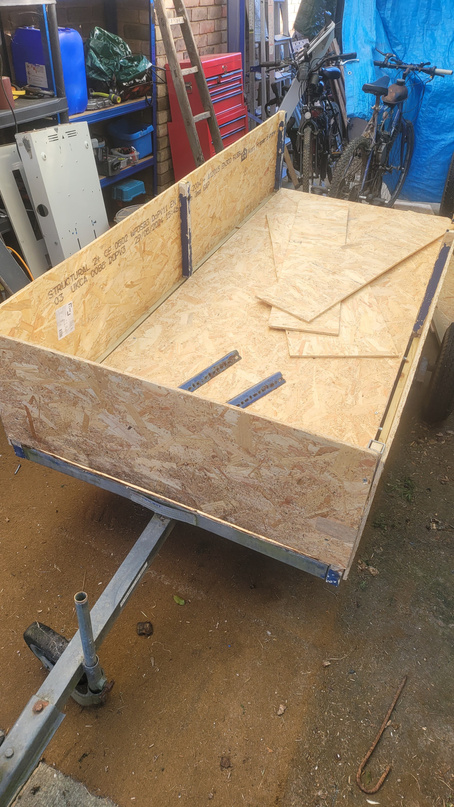 The custom trailer under construction &mdash; OSB bed and side panels mid-build in the workshop