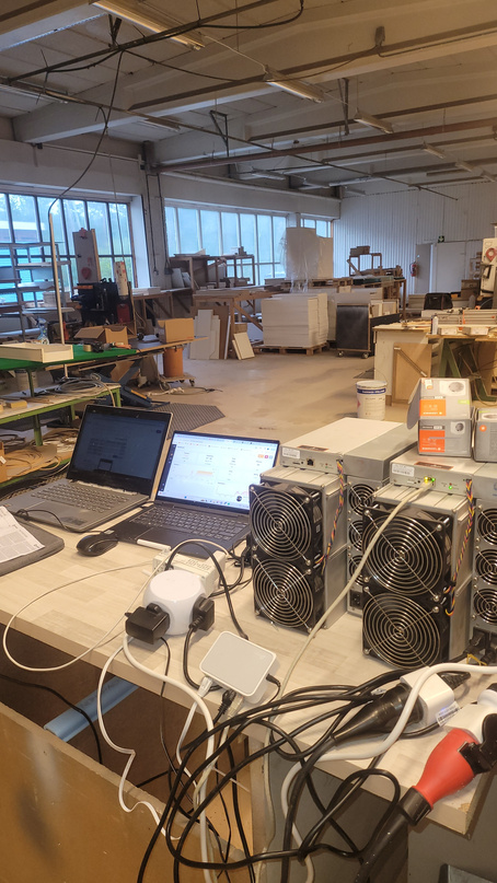 ASIC miners being bench-commissioned with laptops on an industrial unit